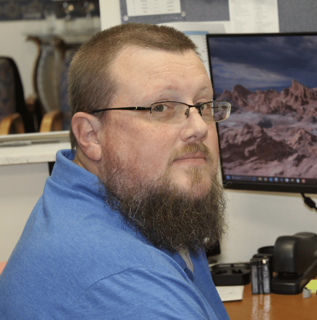 Sam Leslie at a desk with a computer monitor.