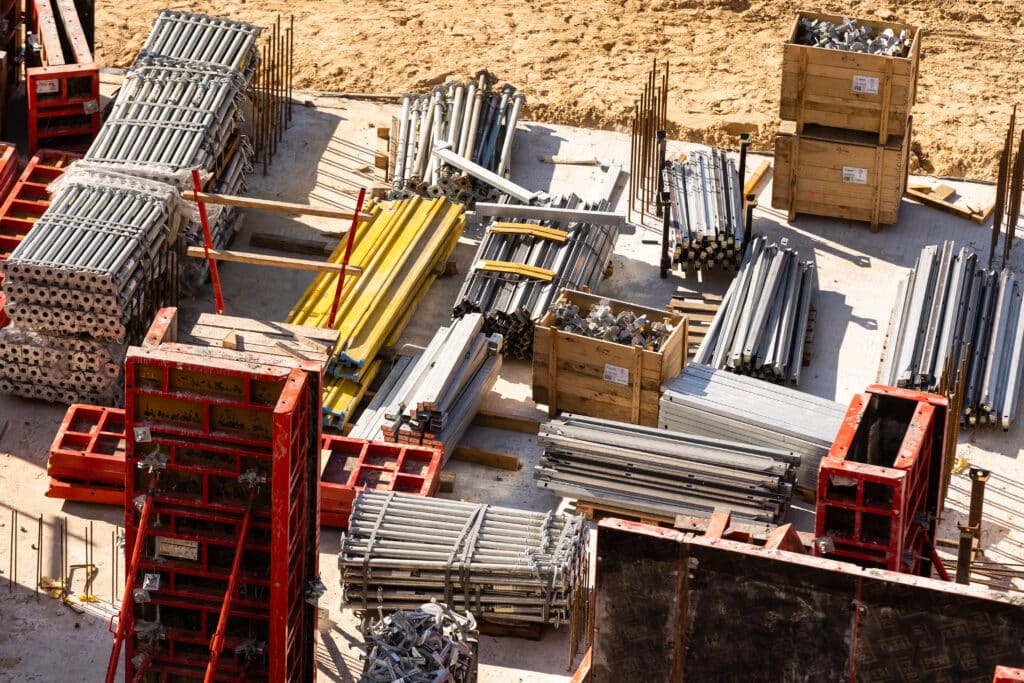 Construction materials and equipment organized at a residential complex construction site.