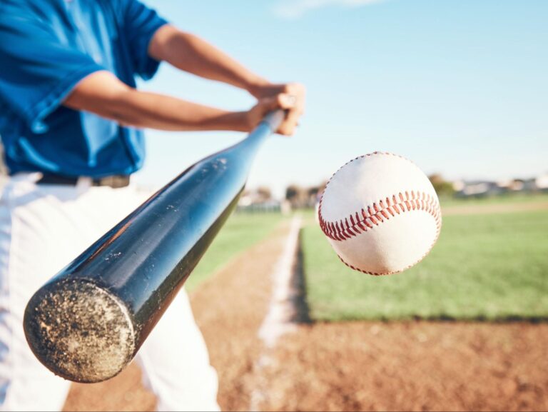 Baseball player swinging bat to hit a ball on the field.