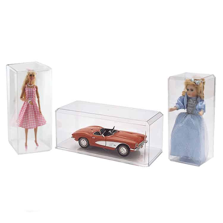 Barbie dolls and vintage car collectible displayed in protective cases.