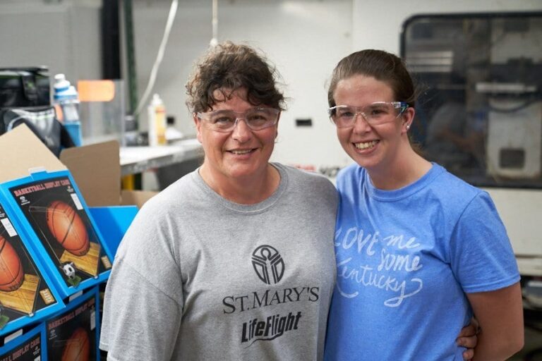 Two smiling Pioneer Plastics team members on the production floor