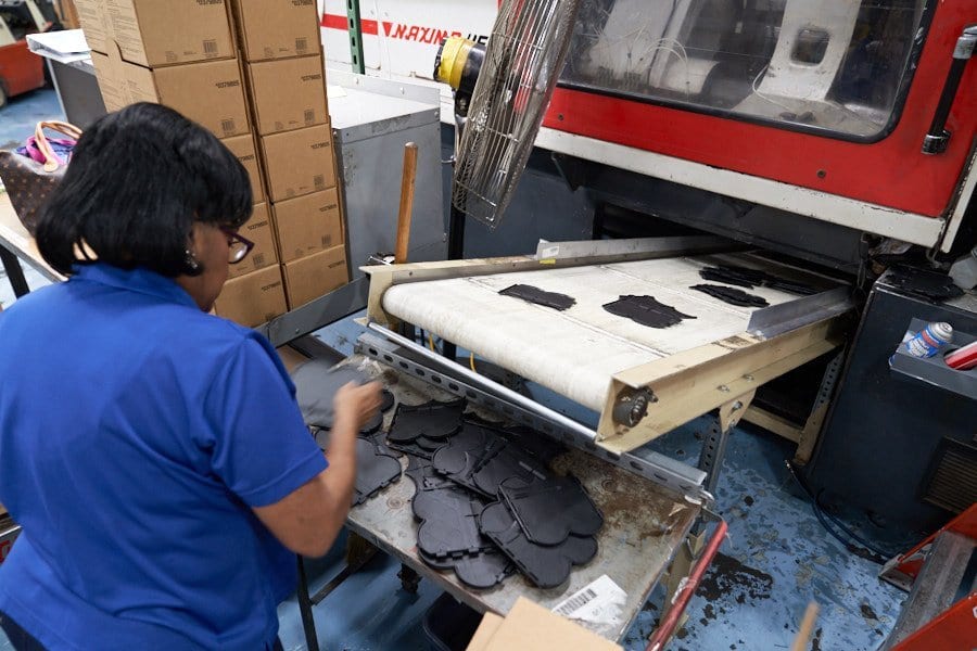 Pioneer Plastics team member trimming molded parts at a press