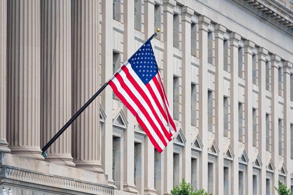 American flag waving proudly on a historic buildings facade.