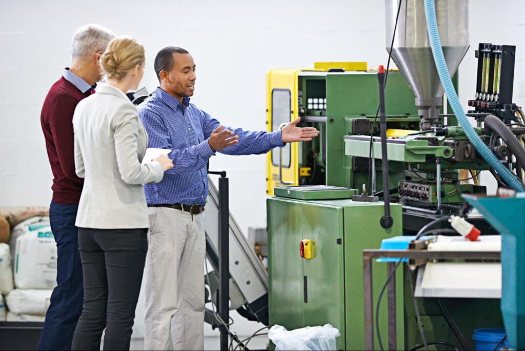 Professionals discussing custom injection molding machine in a manufacturing facility.