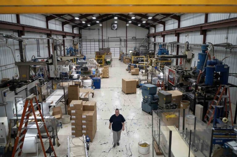 Spacious warehouse with machinery and materials for plastic manufacturing and storage.