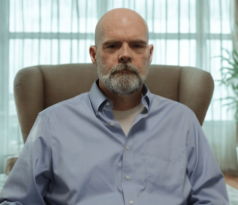 Serious man in armchair, showcasing thoughtful expression in a cozy setting.