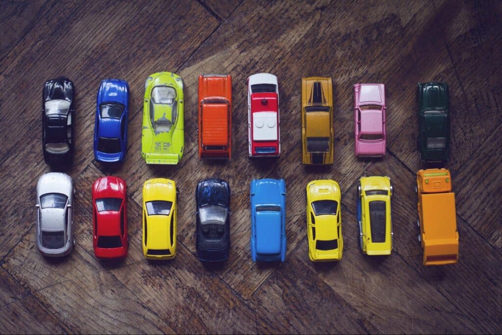 Colorful toy cars arranged creatively on a wooden surface.