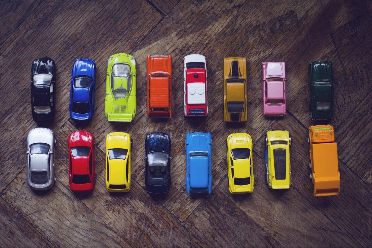 Colorful toy cars arranged creatively on a wooden surface.