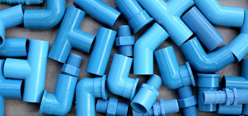 Various blue PVC pipes and fittings arranged on a surface.