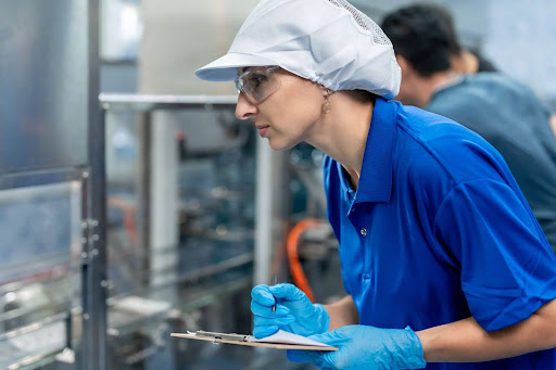 Factory worker taking notes in a production facility for quality control and safety measures.