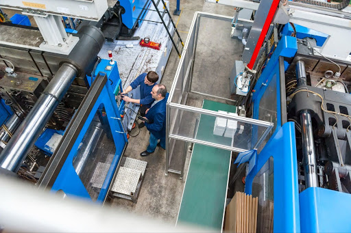 Workers operate advanced industrial machinery in a modern manufacturing facility.