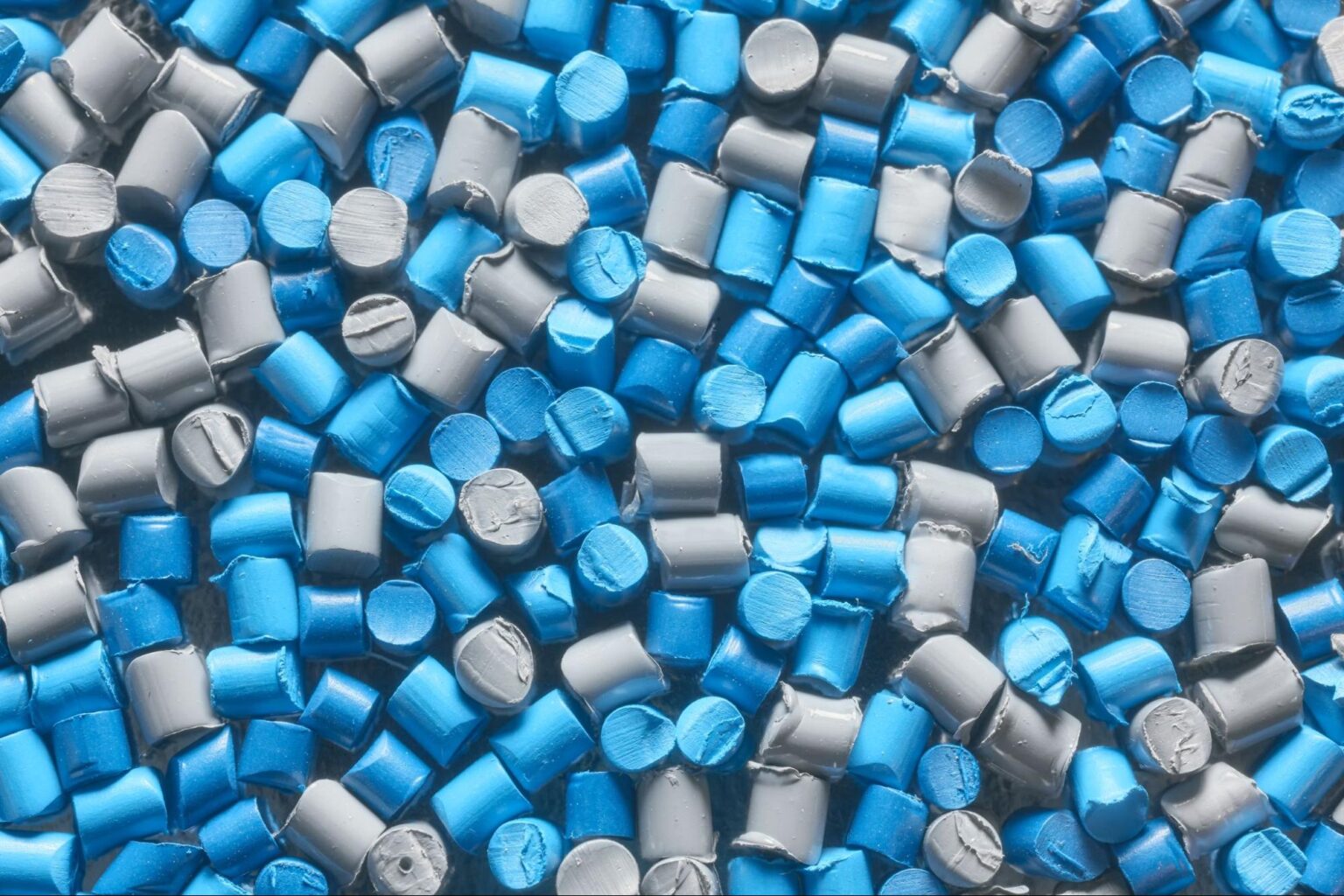 Colorful blue and gray plastic pellets for manufacturing and recycling processes.