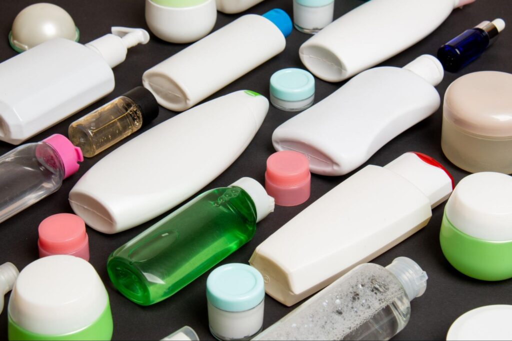 Assorted skincare and cosmetic bottles made from polypropylene pellets in injection molding arranged on a dark surface.