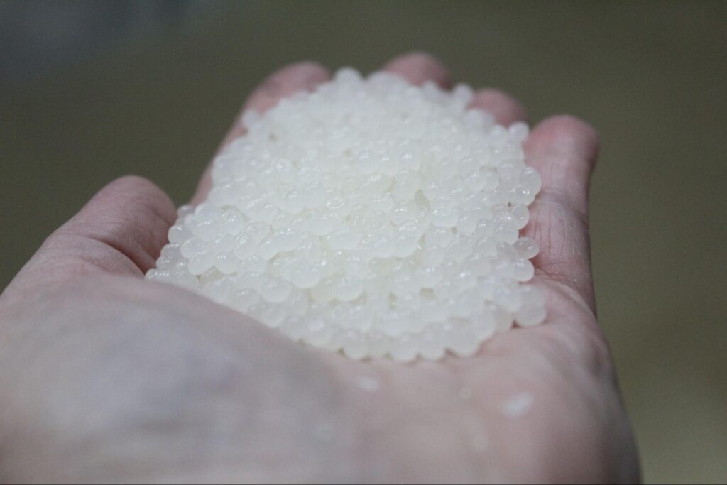 Handful of white resin pellets in hand