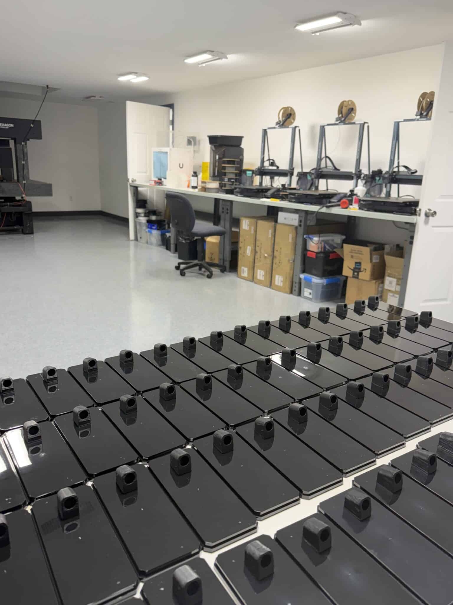 Bank of FDM 3D printers with filament spools at Pioneer Plastics Design Center